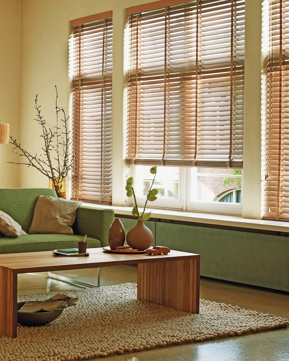 Sala com sofá verde e persiana horizontal de madeira em janela ampla