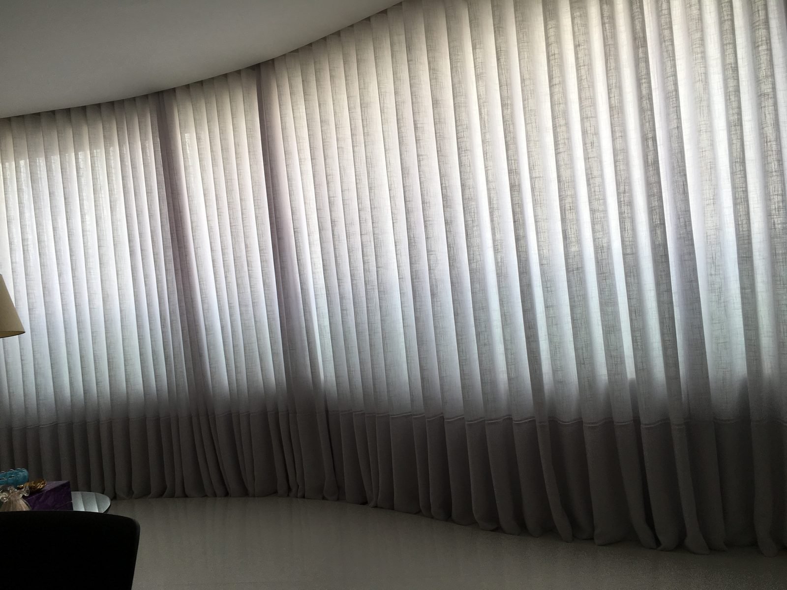 Detalhe de cortina wave instalada em parede curva, mostrando as ondas uniformes do tecido